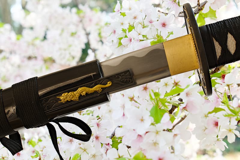 Afilada katana de madera con vaina (saya 鞘), provista de funda protectora de tela | Como dice el refrán: "La flor más bella es el cerezo en flor, el mejor hombre es el guerrero" (花は桜木人は武士).