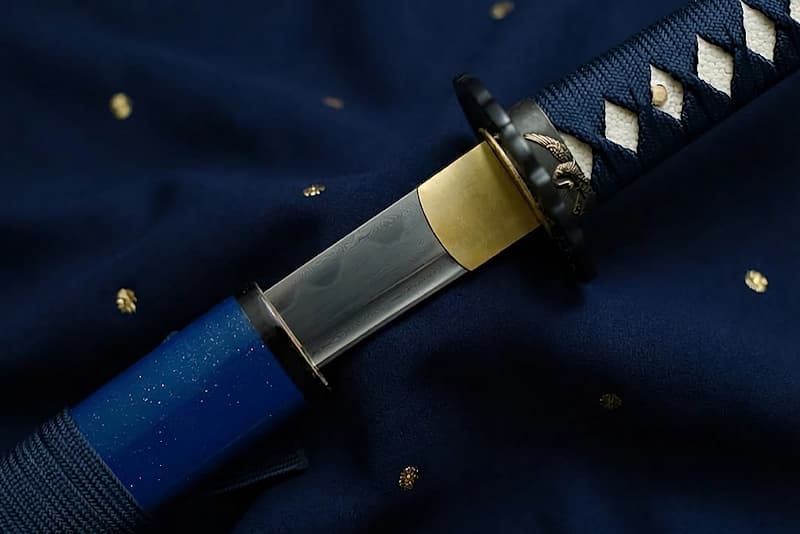 Wakizashi afilado, acero laminado (forja damasquinada), auténtico Hamon (刃文 línea de templado), forjado, pulido y afilado a mano, saya azul y puntas doradas.