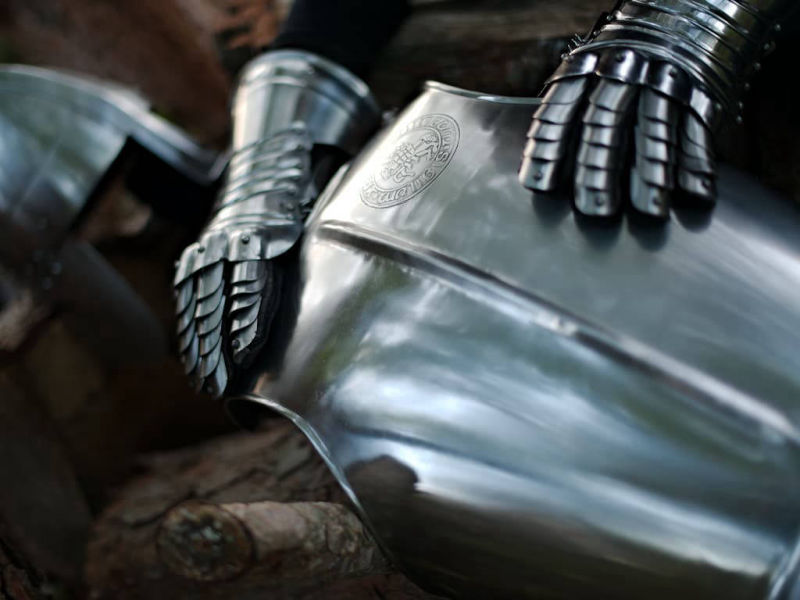 Coraza con el sello templario en relieve, escenificada con un par de guanteletes y un casco medieval Coraza con el sello templario en relieve, escenificada con un par de guanteletes y un casco medieval