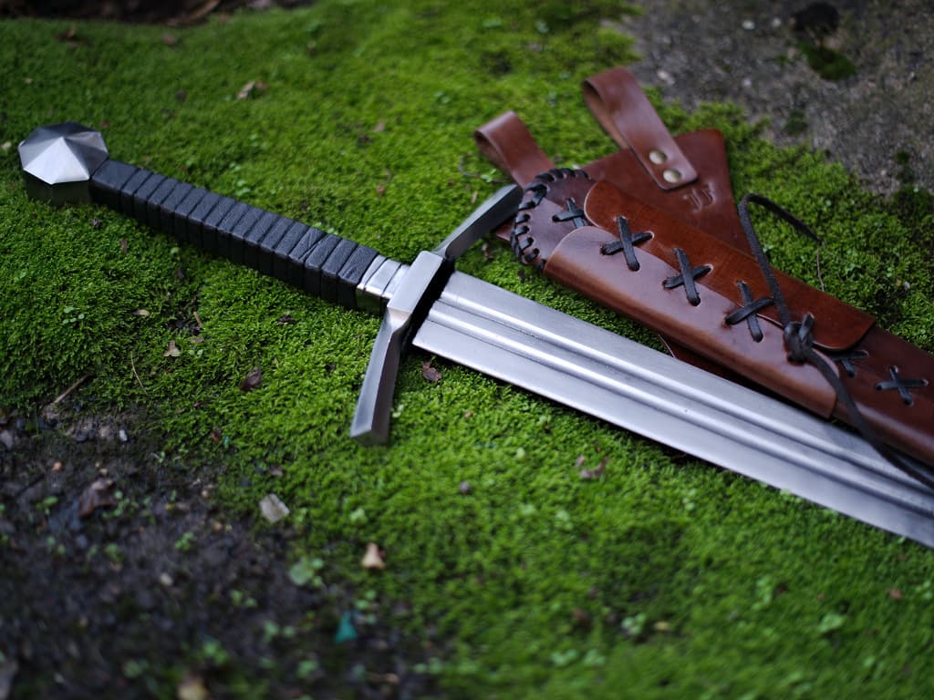 Espada medieval forjada con vaina de cuero marrón con cordones