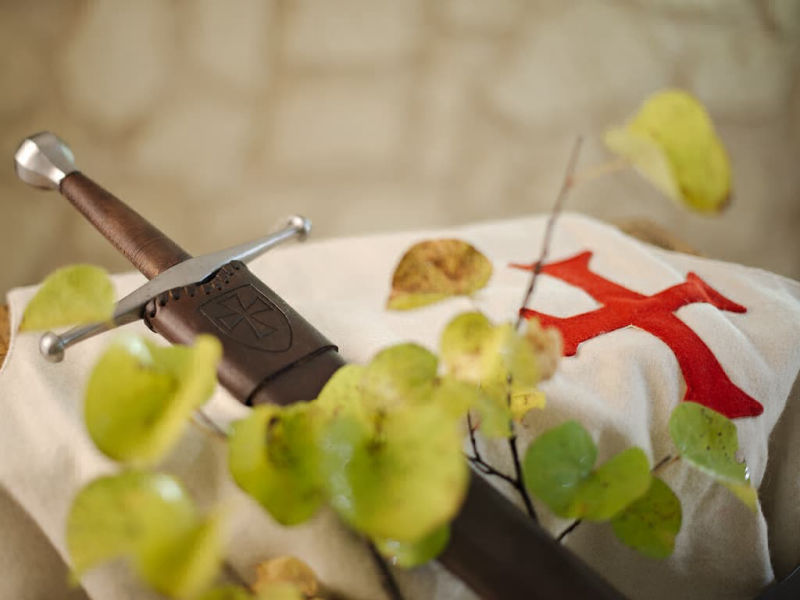 Espada medieval forjada con tabardo de lana blanca con la cruz templaria.