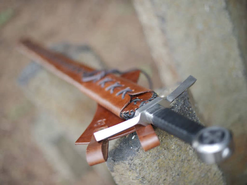 Espada de caballero medieval cruzada engastada sobre piedras naturales verticales