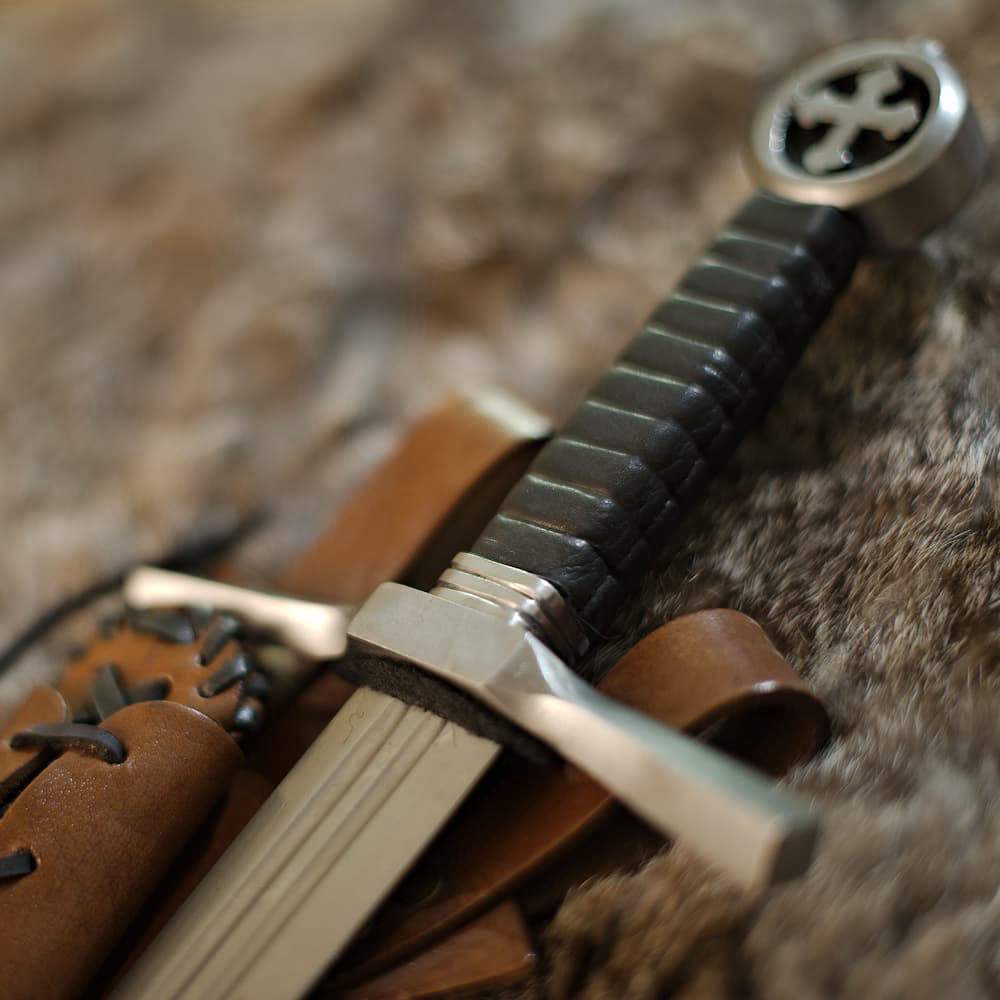 Daga medieval de caballero cruzado (daga de combate con pomo de cruz trilobulada y vaina de cuero marrón con cordones, inclinada)