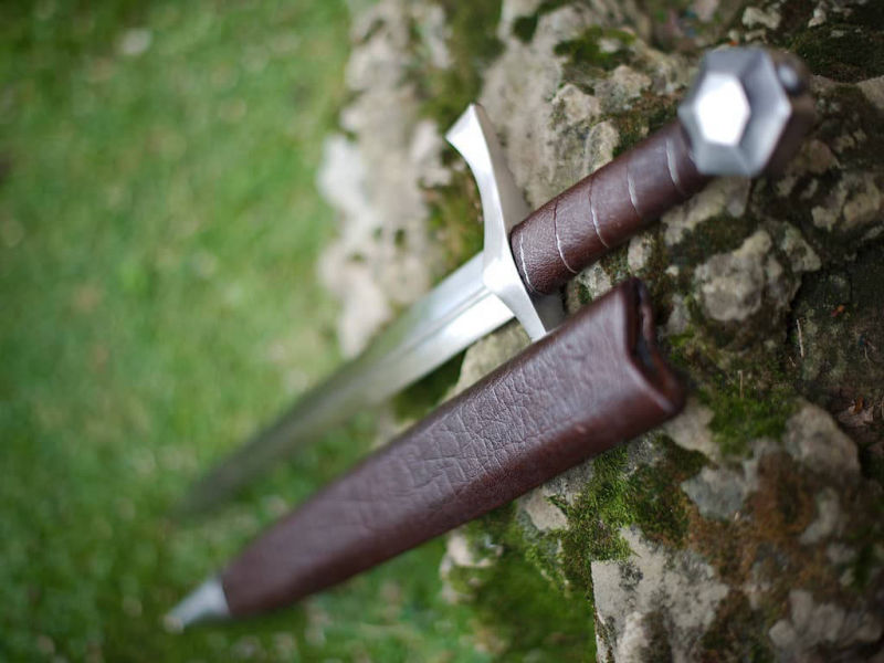 Daga de combate medieval "Lightbane" apoyada en una roca cubierta de musgo natural