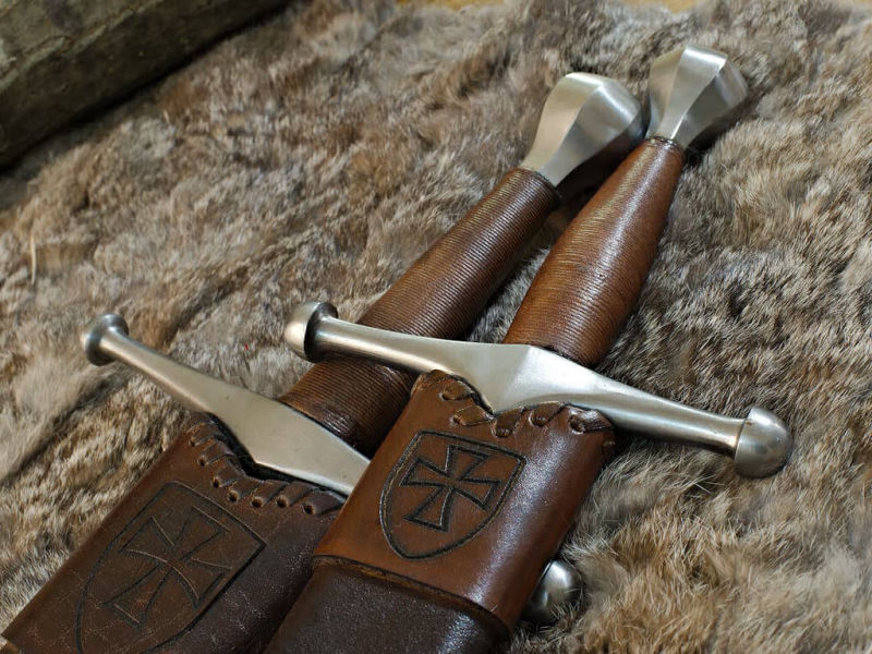 Épée et dague médiévale allemande, posées sur une peau naturelle Épée et dague médiévale allemande, posées sur une peau naturelle