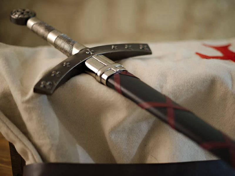 L'épée de la Septième Croisade posée sur un tabard blanc de chevalier croisé L'épée de la Septième Croisade posée sur un tabard blanc de chevalier croisé