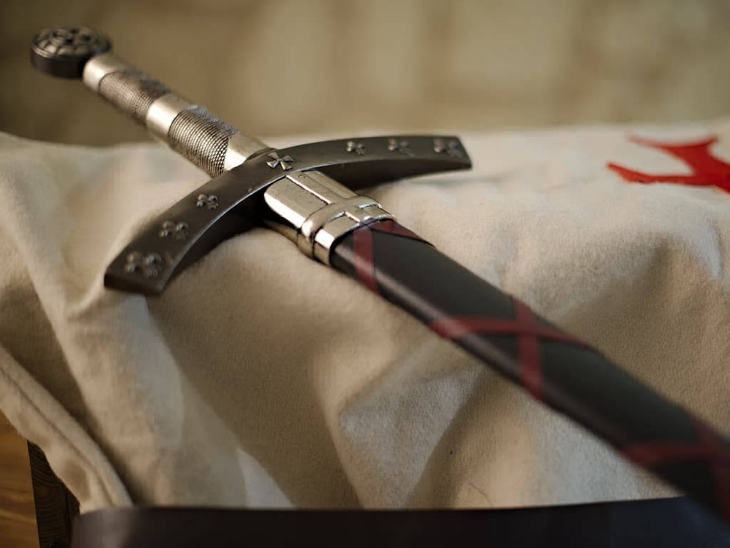 L'épée de la Septième Croisade posée sur un tabard blanc de chevalier croisé L'épée de la Septième Croisade posée sur un tabard blanc de chevalier croisé