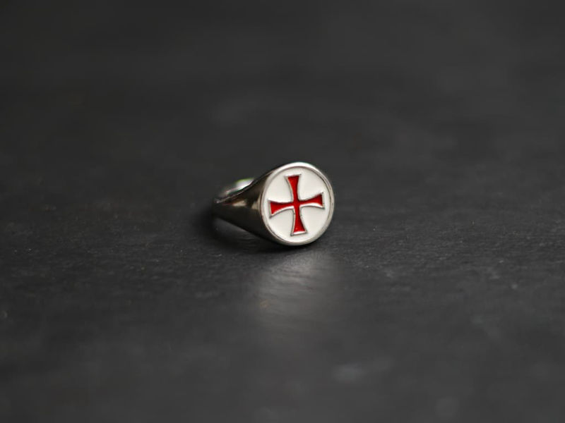 Une main protégée d'un gantelet médiéval prend possession de l'épée templière de décoration Bague croix templière rouge cerclée #Terressens