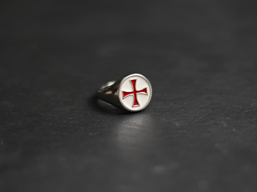 Une main protégée d'un gantelet médiéval prend possession de l'épée templière de décoration Bague croix templière rouge cerclée #Terressens