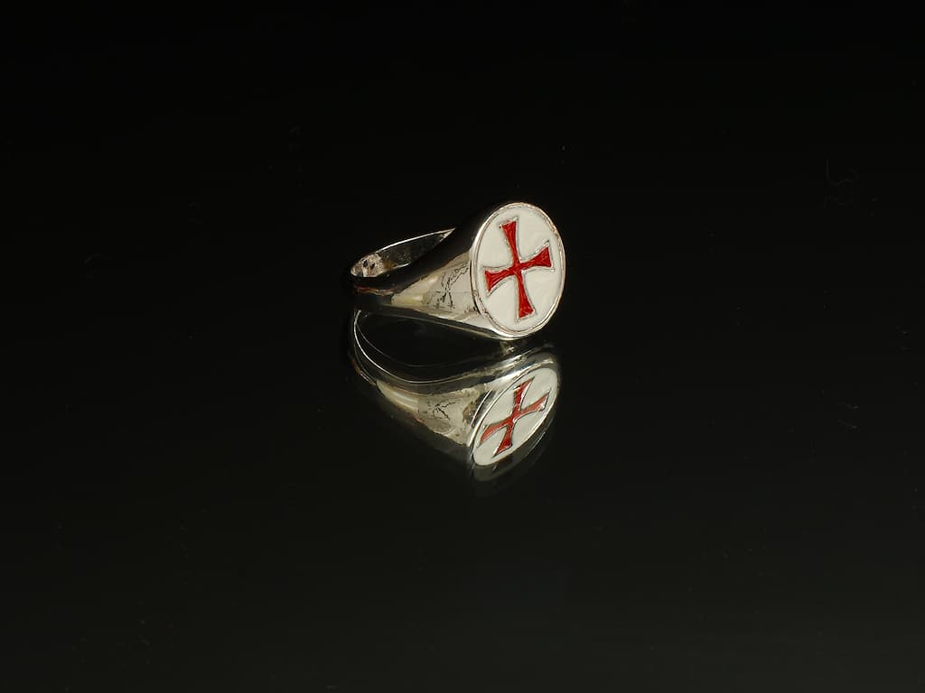 Épée templière de décoration posée sur un rocher avec un arrière-plan en mousse végétale Bague croix templière rouge cerclée #Terressens